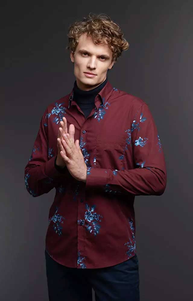Mężczyzna w eleganckiej bordowej koszuli ze złożonymi dłońmi